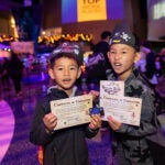 Two boys showing their scavenger hunt certificate of completion